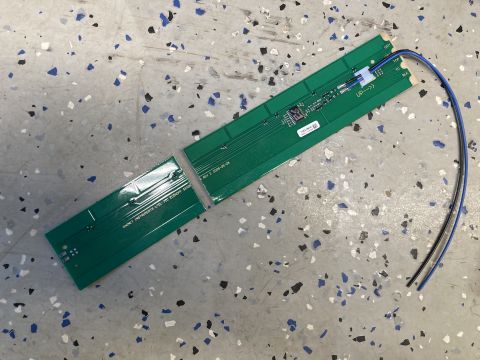 2015 Ford F-550 - A broken green circuit board with visible components and wires lies on a textured floor.