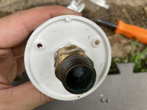 2015 Ford F-550 - A hand holds a brass water fitting connected to a white housing, with a screwdriver in the background.