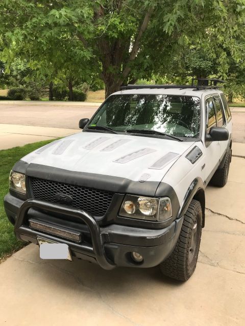 2000 Ford Explorer - This modified Ford Ranger SUV is parked in a residential driveway, a custom grille and aftermarket lights.