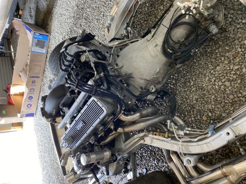 1976 Chevrolet Corvette - This image shows an engine and transmission assembly, a valve cover with '496' inscribed on it.