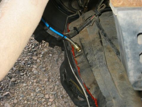 1994 Ford Bronco - A close-up view of a vehicle's undercarriage shows a blue hose and a leak of red fluid.