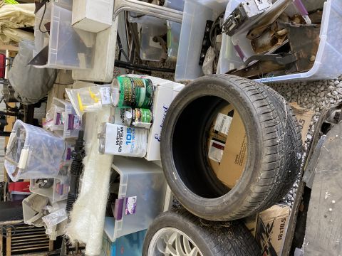 pile of storage bins and car parts, including a tire and a car wheel