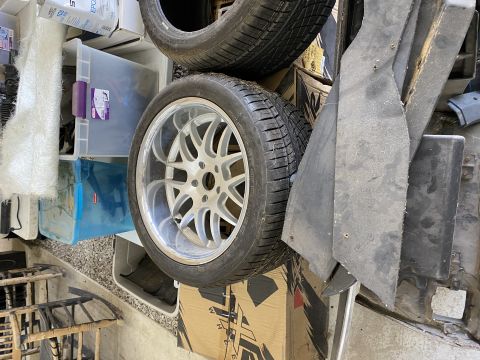Car wheel and tire stacked on storage bins with black car parts