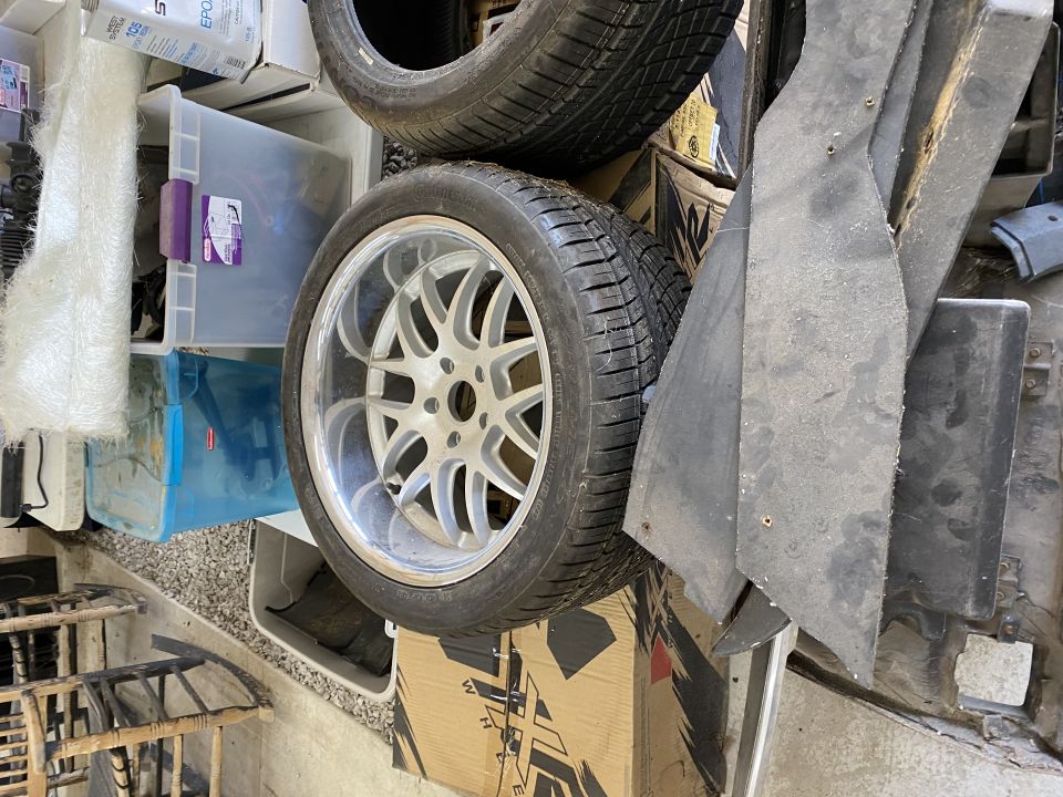 Car wheel and tire stacked on storage bins with black car parts