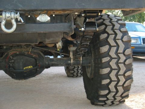 1994 Ford Bronco - This photo shows the rear suspension and axle of a vehicle, with another car in the background.