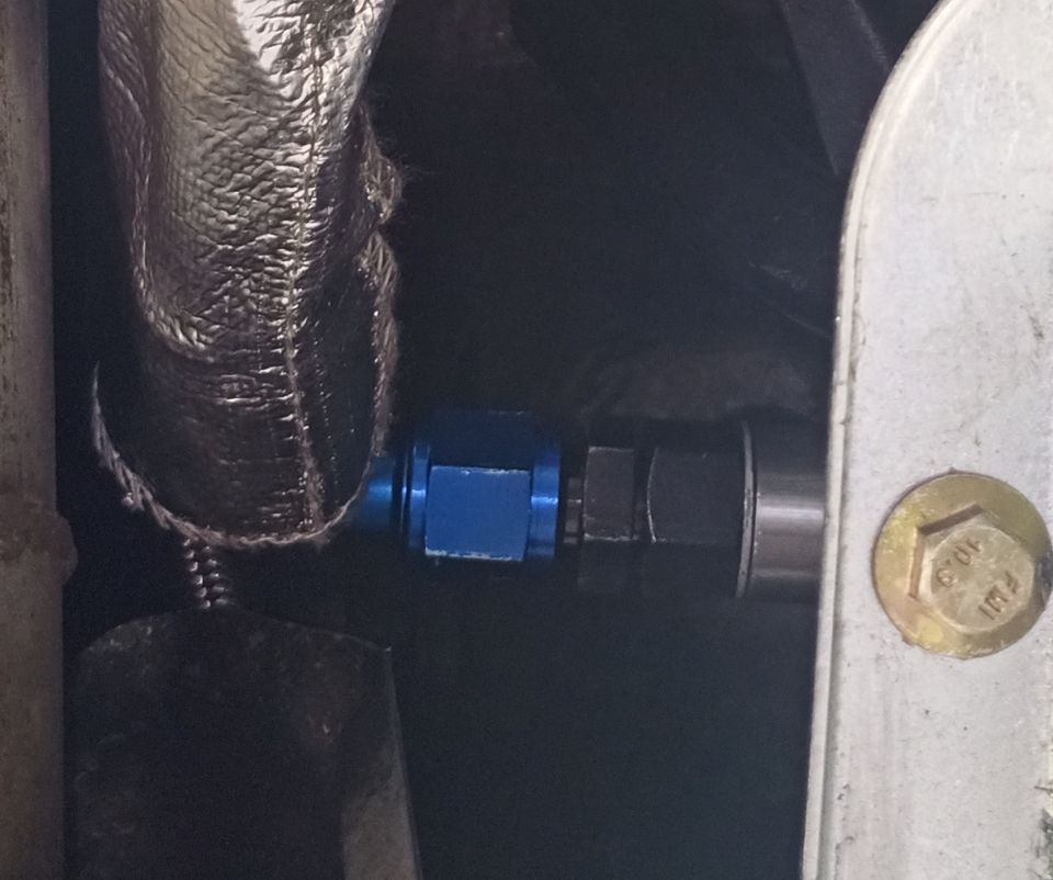 Blue AN fitting on a transmission cooler line, with heat-reflective wrap
