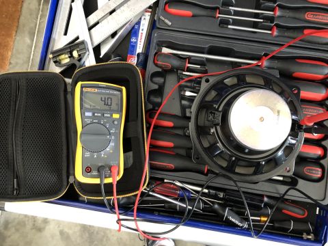 2019 Ford Everest - A multimeter is used to test the resistance of a car speaker, surrounded by various tools.