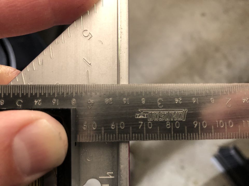 Close-up of a metal ruler and square being used to measure a metal edge