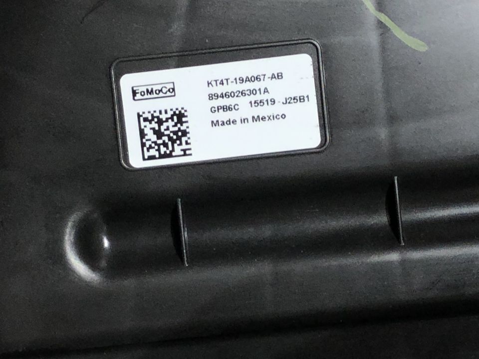 Black plastic part with a white label showing 'FoMoCo' and part number KT4T-19A067-AB