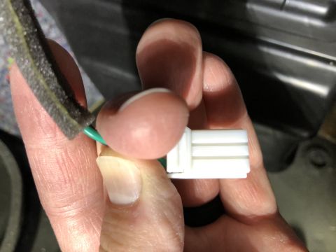 2019 Ford Everest - A close-up shows a hand holding a white electrical connector with a green wire, likely for a vehicle component.