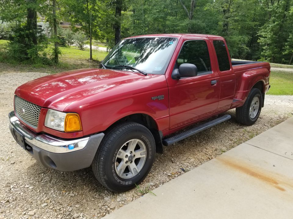 Red Ford Ranger XLT extended-cab pickup parked on gravel driveway