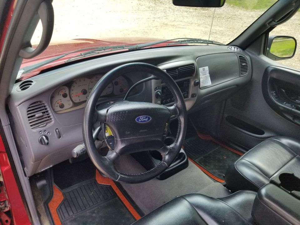 Ford Ranger interior from driver's side showing steering wheel, gray dash, gauges, and black leather seats