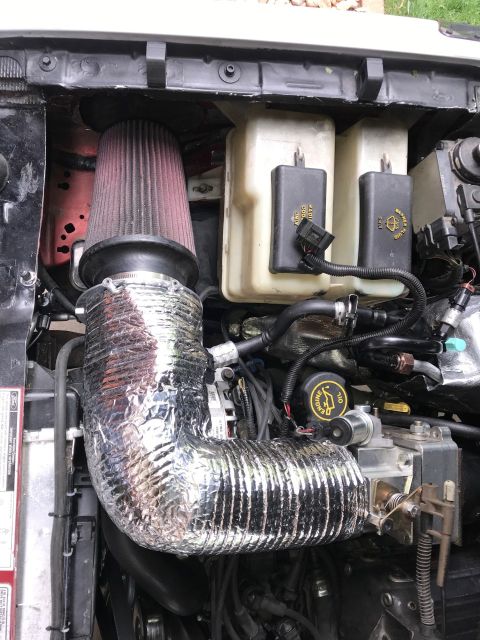 2000 Ford Explorer - Close-up of an engine bay showing an aftermarket air intake system installed.