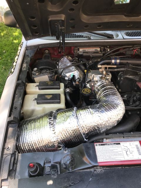 2000 Ford Explorer - Close-up view of the engine bay of a 2000 Ford Explorer, focusing on the intake system with a large, silver, insulated flexible tube. The h…