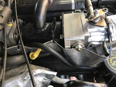 2000 Ford Explorer - A close-up view of an engine bay shows a black intake pipe connected to a silver component, with heat shielding around a black hose and a y…