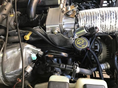 2000 Ford Explorer - A close-up view of the engine bay of a 2000 Ford Explorer, showing various components including the oil cap, alternator, and heat shielding.