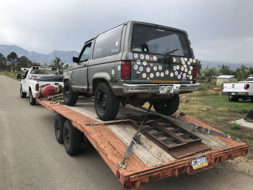 1988 Ford Bronco II with stickers on rear hatch, loaded on a trailer.