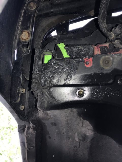2000 Ford Explorer - A close-up view shows a damaged black plastic fender liner with black sealant and green tape applied to repair a tear. Rusty bolts and a re…