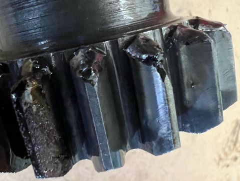 1979 Jeep CJ5 - Close-up view of a damaged metal gear with chipped teeth, possibly from a vehicle's drivetrain.