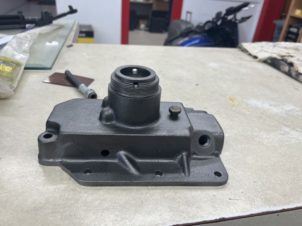 Dark gray cast metal automotive part with threaded sections and bolt holes