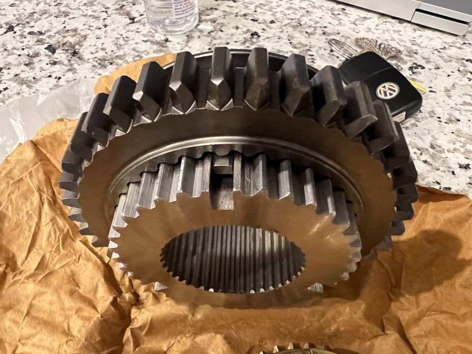 Two large metal gears on brown paper with car keys in the background.