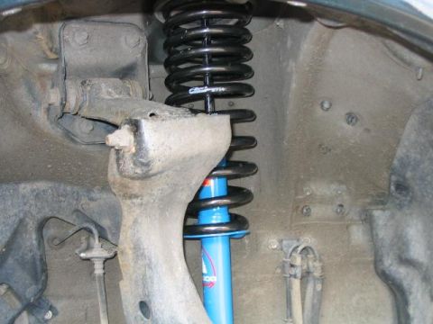 1986 Ford F-150 - The image shows the front suspension of a vehicle, including a blue shock absorber and a black coil spring.