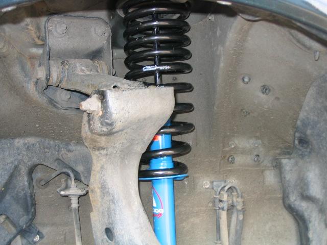 Close-up of a vehicle's front suspension with a blue shock absorber and black coil spring