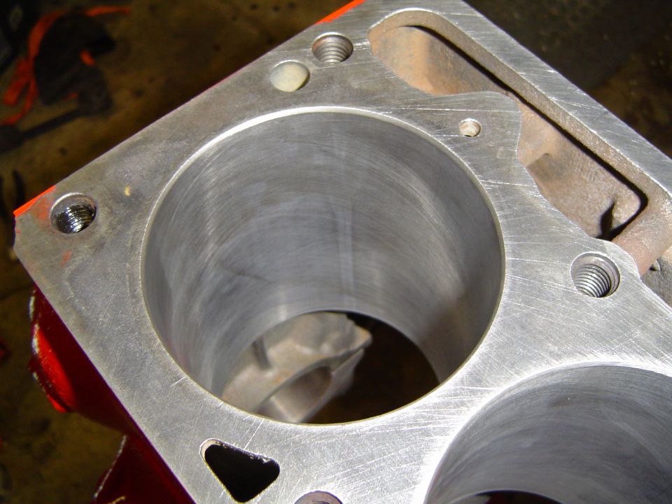Corner of aluminum engine block showing two bored cylinders and head-bolt holes