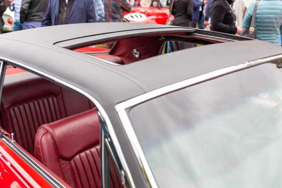 Close-up of red car interior with open sunroof and red leather seats.
