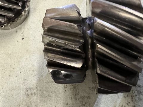 1979 Jeep CJ5 - Close-up view of two damaged metal gears, likely from a transmission, resting on a light-colored, textured surface. One gear is significant…