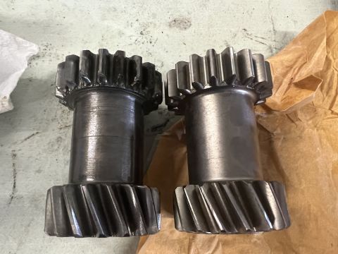 1979 Jeep CJ5 - Two metal gears with helical teeth are shown side-by-side on a light-colored surface next to brown paper.