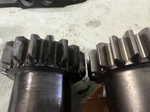 1979 Jeep CJ5 - Two metal gears are shown in close-up. The gear on the left appears worn and damaged, with chipped teeth, while the gear on the right shows…