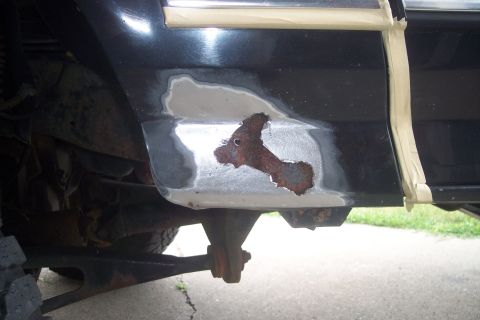 1995 Ford Bronco - The underside of a vehicle reveals worn suspension parts and a rusty wheel well.