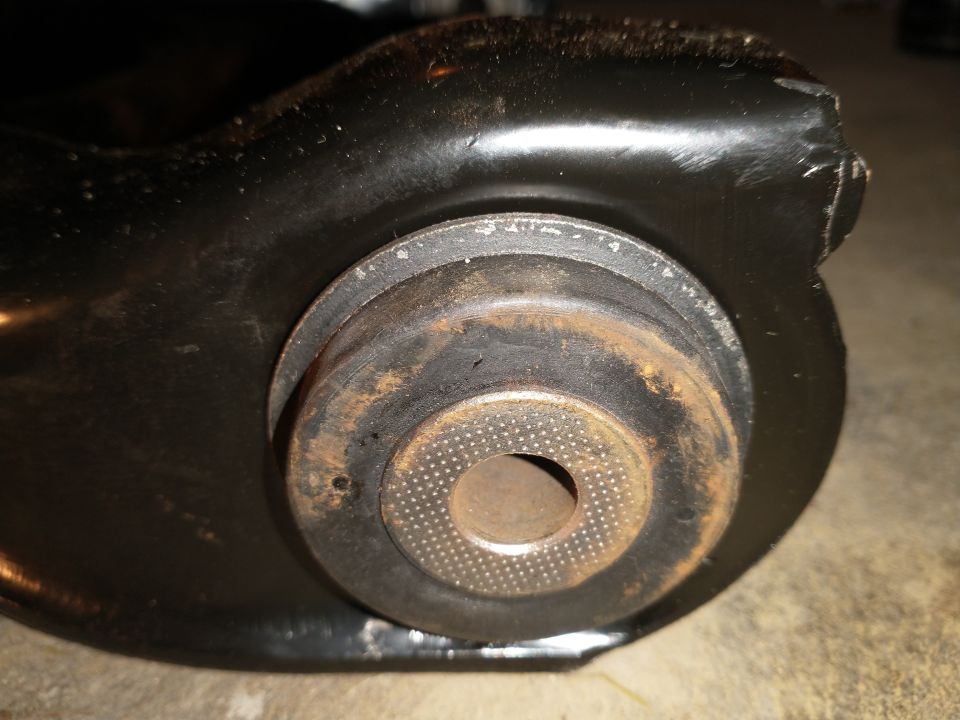 Close-up of a rusty suspension component with a circular metal part showing a textured surface