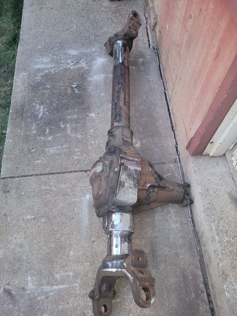 1995 Ford Bronco - Front axle assembly, likely from a 4x4 vehicle, resting on concrete.