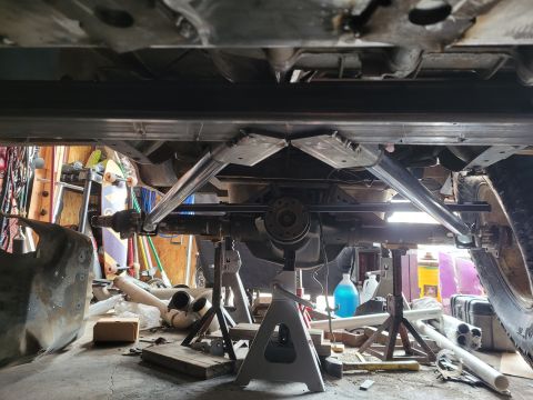1995 Ford Bronco - The undercarriage of a vehicle is visible, supported by jack stands, with modifications to the suspension system.