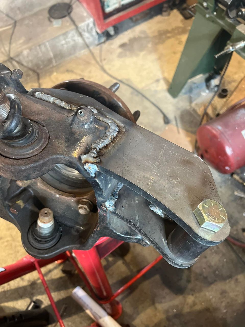 Modified suspension part with welds and a large bolt
