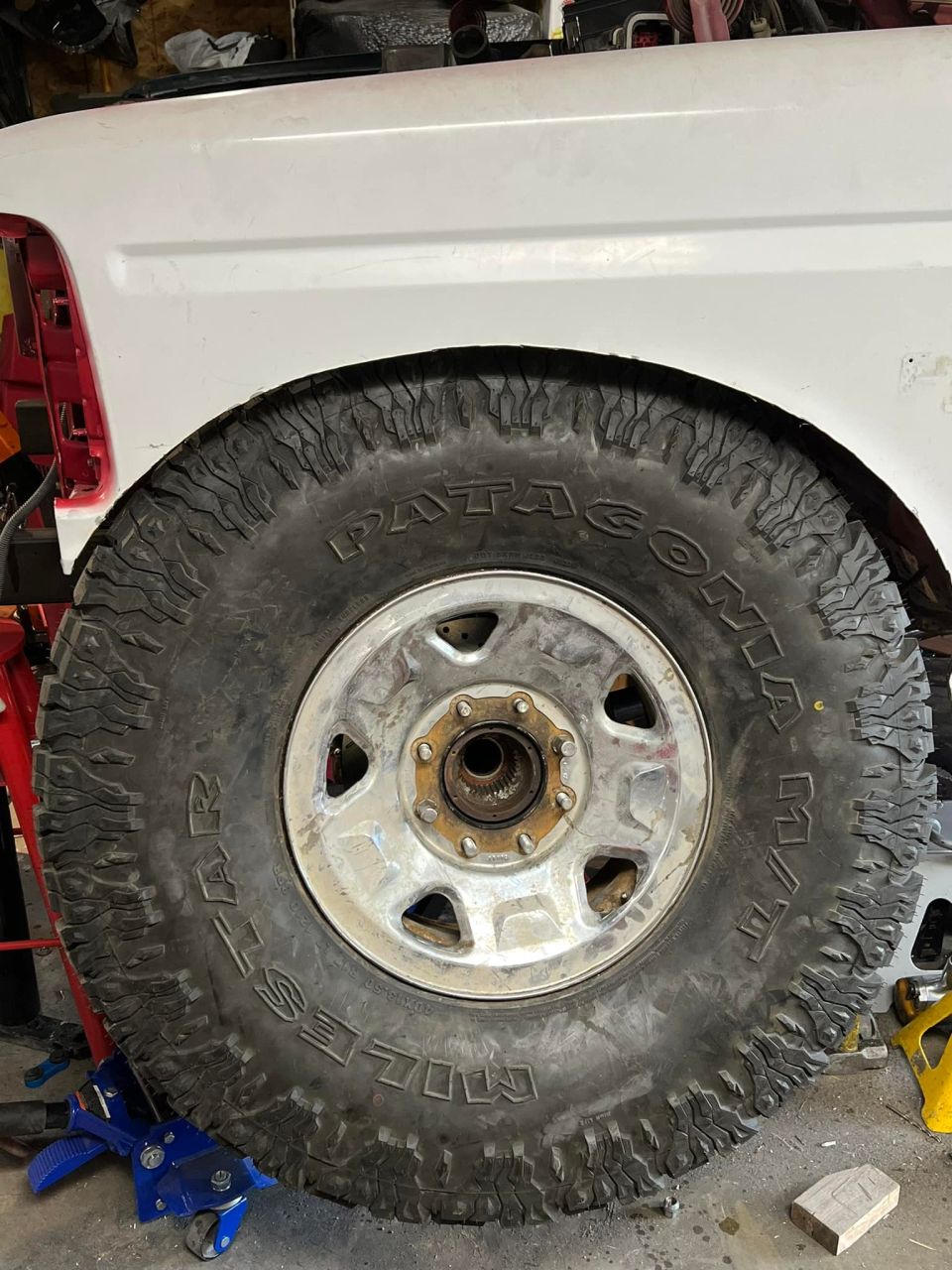Close-up of a Patagonia Milestar tire on a chrome rim under a white vehicle fender.