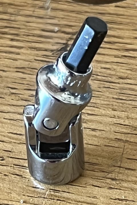 1975 Ford Ranchero - A close-up shot shows a chrome universal joint socket adapter with a black hex bit inserted. The tool is resting on a wooden surface.