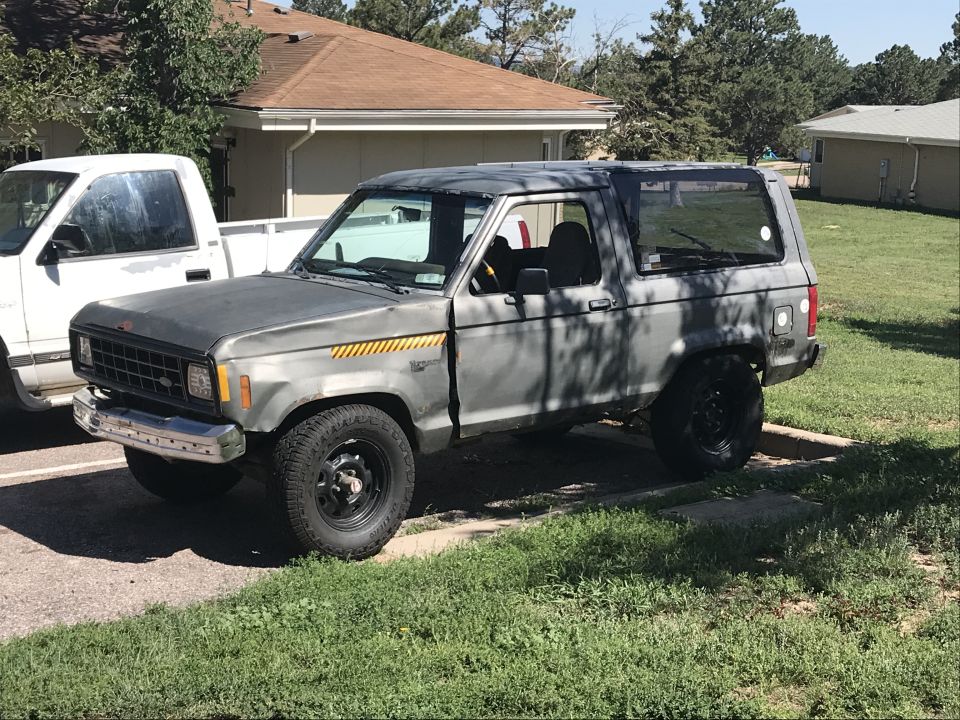 1980s Ford Bronco II, driver's side view, dark gray, parked on grass