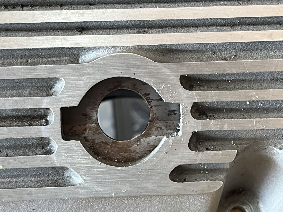 Close-up of a metal part with fins and a circular opening, showing wear.
