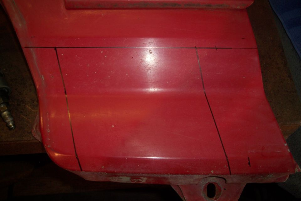 Red plastic vehicle part with black cut lines marked for modification.