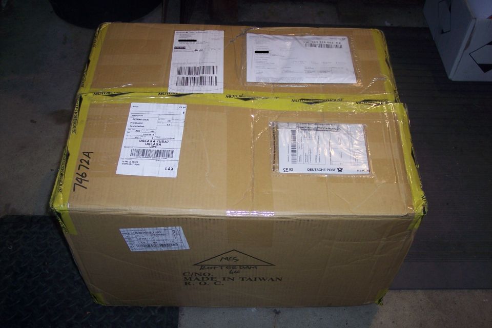Cardboard shipping box with multiple labels and yellow tape.