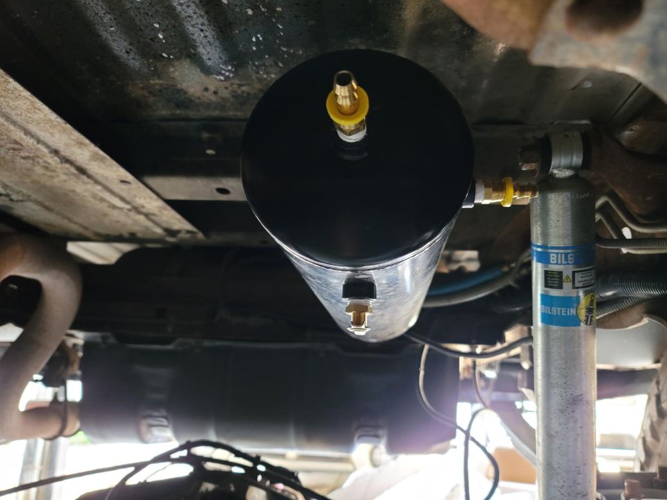 Undercarriage of a vehicle showing an air tank and a Bilstein shock absorber.