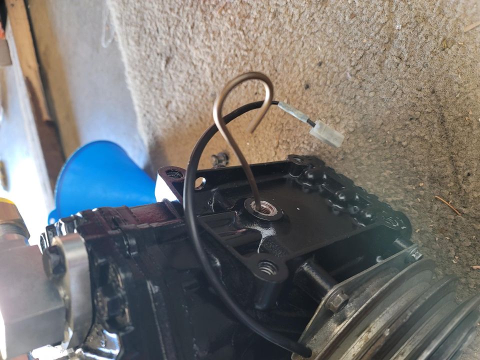Close-up of black engine part with chain and wire loop.