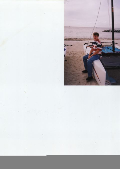 1982 Ford Bronco - A young person sits on the side of a sailboat pulled up onto a sandy beach.