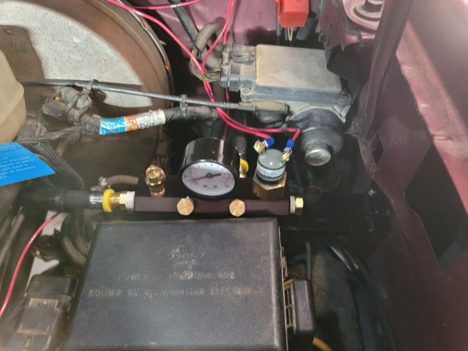 On-board air compressor manifold with gauge and solenoid, mounted near a Ford power distribution box