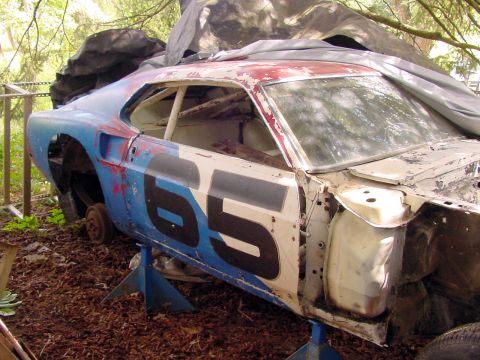 1969 Ford Mustang - This heavily modified race car, possibly a 1970 model, is in a state of disrepair and stored outdoors.