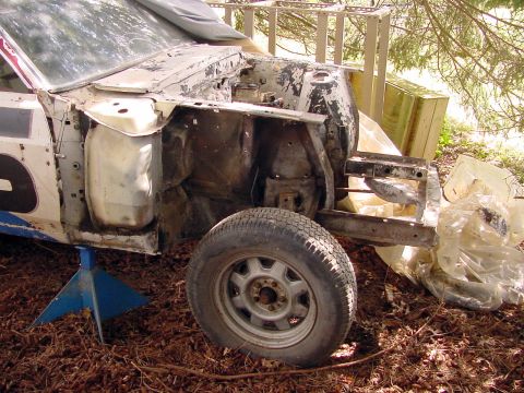 1969 Ford Mustang - The front end of a 1969 Ford Mustang chassis is visible, supported by blue jack stands and surrounded by debris.