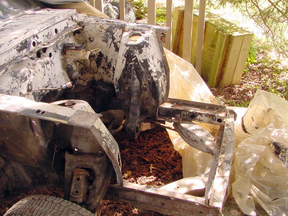 Stripped truck front clip and frame with mud, body panels removed